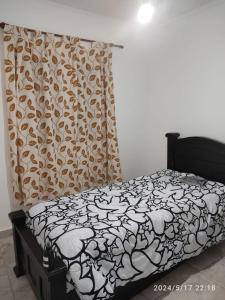 a bedroom with a bed with a black and white blanket at Departamento la India 1 Temporario in San Fernando del Valle de Catamarca