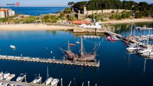 a boat docked next to a dock with boats in the water at Baiona Curuxa in Baiona