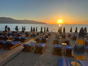 a beach with lounge chairs and umbrellas at sunset at Sunny beach Jonufer in Vlorë
