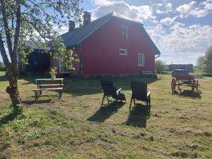 un fienile rosso con sedie e un tavolo nel cortile di Grotini a Ķipari