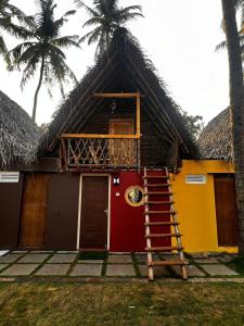 a house with a thatched roof with a staircase and palm trees at The Nature swimming resort in Puducherry