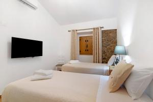 a hotel room with two beds and a flat screen tv at Casas do Monte I - T2 in Mértola