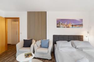 a living room with a bed and two chairs at Nette kompakte Wohnung mit Balkon in Pforzheim