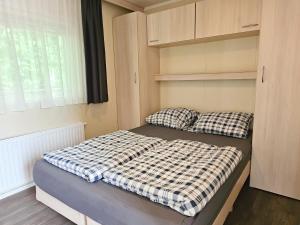 a bed with two pillows in a small bedroom at Familie Chalet Oostkapelle OK30 in Oostkapelle