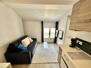 uma sala de estar com um sofá preto numa cozinha em Charmant T2 à deux pas du cours Mirabeau em Aix-en-Provence