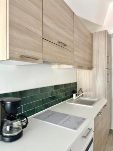uma cozinha com armários de madeira e um lavatório branco em Charmant T2 à deux pas du cours Mirabeau em Aix-en-Provence mais 4 fotografias