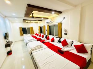 a row of beds in a room with red pillows at Hotel Sawai Executive Branch 3 in Sāsvad