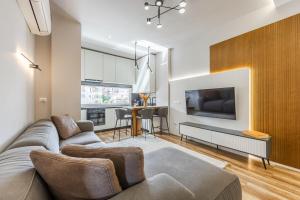 a living room with a couch and a tv at Chloe's Central Apartment in Durrës