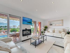 Una sala de estar con muebles blancos y un televisor. en Villa Nina Marbella, en Marbella