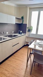 a kitchen with white cabinets and a table with chairs at La CASA del PORTO ANTICO in Genoa