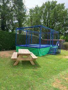 a picnic table next to a blue batting cage at OPHEA 4 personnes in Limeuil