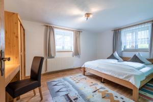 a bedroom with a bed and a desk and a chair at DORF 77 Apartment in Elbigenalp