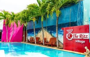 威廉斯塔德The Ritz Hostel的一座建筑前的游泳池,里面设有椅子和棕榈树