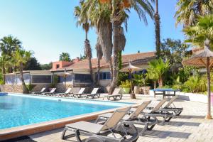 a pool with chairs and a table and palm trees at Très beau T2 - Emeraude 40 in Canet-en-Roussillon