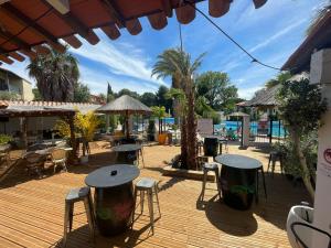 a wooden deck with tables and chairs and a pool at Très beau T2 - Emeraude 40 in Canet-en-Roussillon