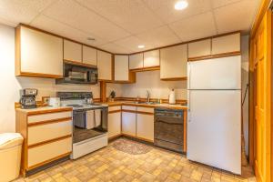 een keuken met houten kasten en een witte koelkast bij Gray Wolf 4 in Whitefish +18 foto's