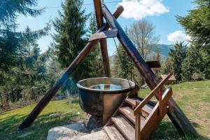 a large bucket on a wooden stand in a field at Complex Turistic Alpina Blazna Sant in Şanţ