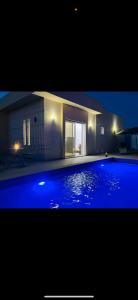 a large swimming pool with blue lighting in front of a house at Villa Lamys Djerba Houmt Souk à 5 minute du centre ville in Al Hara Al Kabira