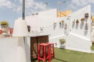 a red stool sitting next to a bar on a patio at Alohamundi Chicarreros Catedral in Seville