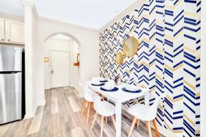 a dining room with a white table and chairs and a geometric wall at 2BR Queen bed Condo - Hot Tub Pool - Near Disney in Orlando