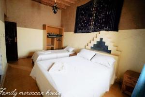 a bedroom with two beds and a painting on the wall at Sahara Desert Experience camp in Merzouga
