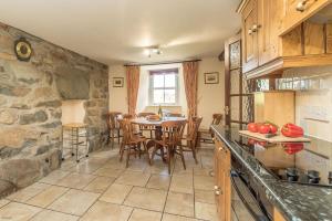 a kitchen with a table and a stone wall at Bwthyn-Betws in Dolbenmaen