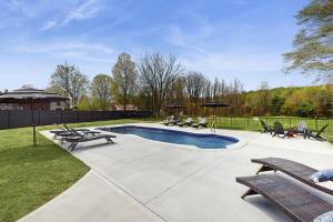 a pool with benches and umbrellas in a yard at The Apartment at the Compound in Fort Ann