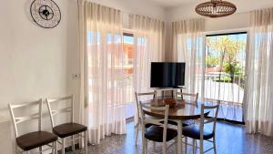 a dining room with a table and chairs and a tv at Las perlas VYBDenia in Denia