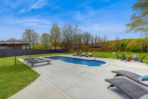 a swimming pool with chairs and umbrellas in a yard at The House at the Compound in Fort Ann