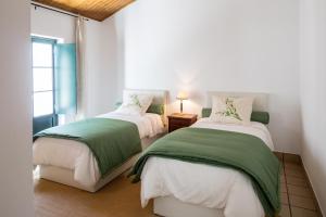 a bedroom with two beds with green and white sheets at Casas de São José in Rio Maior +60 photos