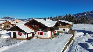 a house covered in snow with mountains in the background at Ferienhaus Alpenherz Sommer-Bergbahnen-kostenlos in Bolsterlang
