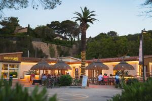 a restaurant with a palm tree in front of a building at Tamarit Beach Resort in Tamarit
