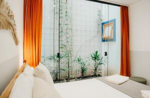 een slaapkamer met een bed en een raam met planten bij Vila Trancoso Perequê in Ilhabela