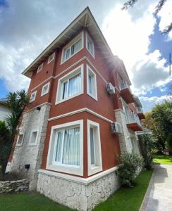 a red brick building with white windows and grass at Valeria Beach in Valeria del Mar