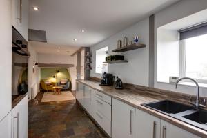 a kitchen with white cabinets and a sink and a couch at The Farmhouse Llyn Peninsula in Pistyll