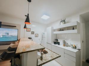 a white kitchen with a counter and a refrigerator at Charmoso apartamento na Lapa in Rio de Janeiro