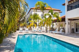 a pool in front of a house with palm trees at Upscale Ocean View Villa with Pool Outdoor Kitchen in Palm-Eagle Beach