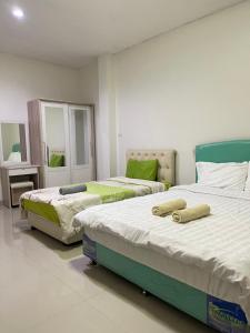 a bedroom with two beds and a mirror at ควีนเพลส สระบุรี Queenplace Saraburi in Sara Buri