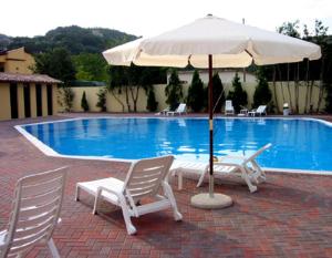 two chairs and an umbrella next to a swimming pool at Hotel Turrita in Arrone