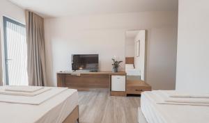 a white room with two beds and a flat screen tv at TIA Layover Rooms in Krujë +4 photos