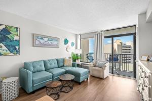 a living room with a blue couch and a balcony at One bedroom ocean front condo - Verandas708 in Myrtle Beach