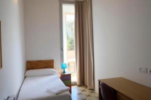 a bedroom with a bed and a desk and a window at Pigal in Tarragona