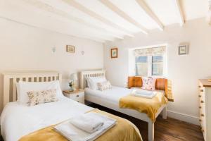a bedroom with two beds and a window at Pass the Keys Cosy Cottage 17th century Garden Parking in Bourton on the Hill