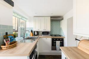 a kitchen with white cabinets and a sink at Pass the Keys Cosy Cottage 17th century Garden Parking in Bourton on the Hill +16 photos