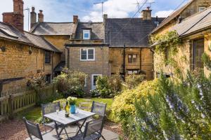 a table and chairs in the garden of a house at Pass the Keys Cosy Cottage 17th century Garden Parking in Bourton on the Hill
