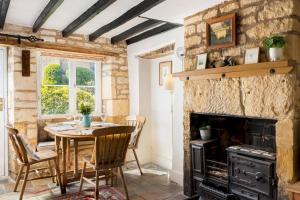 a dining room with a table and a fireplace at Pass the Keys Cosy Cottage 17th century Garden Parking in Bourton on the Hill
