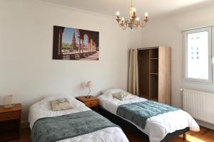 a bedroom with two beds and a chandelier at La Pause Royannaise - 500 m de la plage in Royan