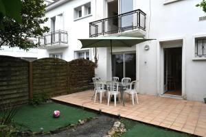 a patio with a table and chairs and an umbrella at La Pause Royannaise - 500 m de la plage in Royan