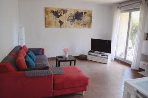 un soggiorno con divano rosso e TV a schermo piatto di Appartement avec Jardin et Terrasse près de Paris a Mantes-la-Jolie