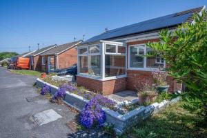 a brick house with flowers in front of it at Cosy Cottage - 2 Bedroom Cottage - Mumbles in Swansea